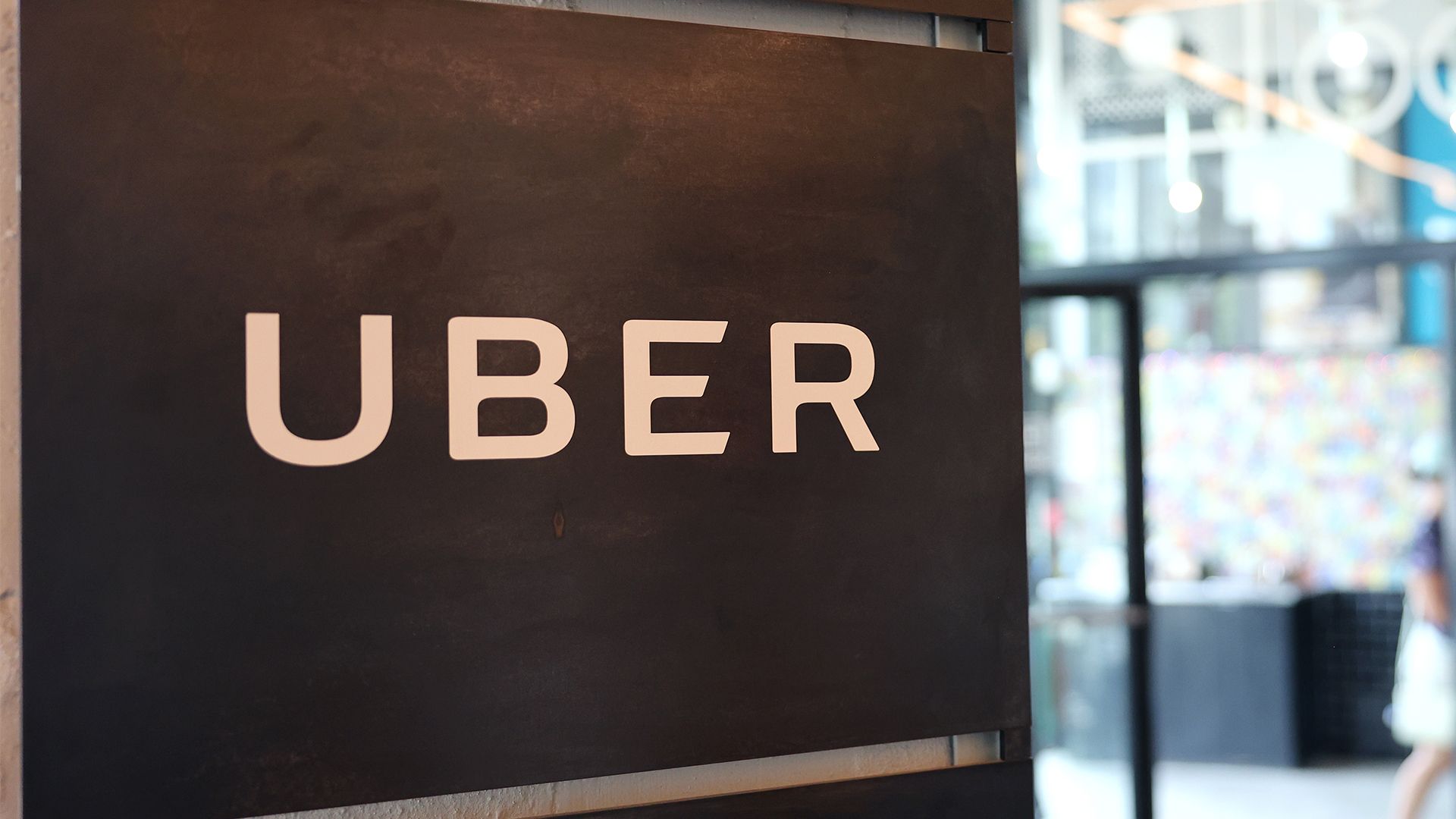 Uber logo pictured on a wall at the Falchi Building in New York City, with pedestrian walking by on the street outside.
